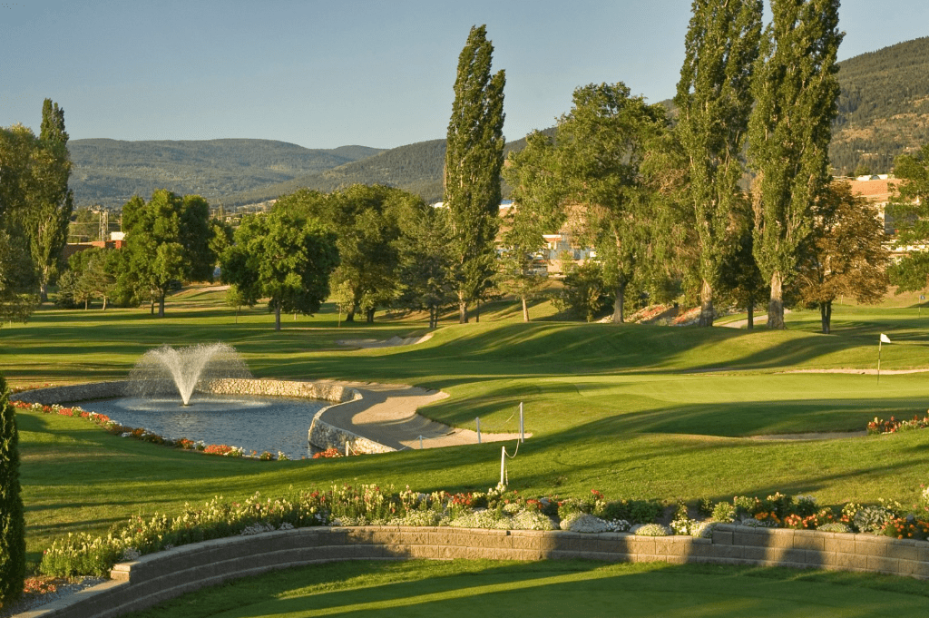 A view of a golf course with water fountain.